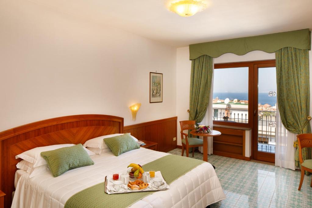 索伦托切萨雷奥古斯托大酒店的一间酒店客房,配有一张床铺,上面放着一个食物托盘