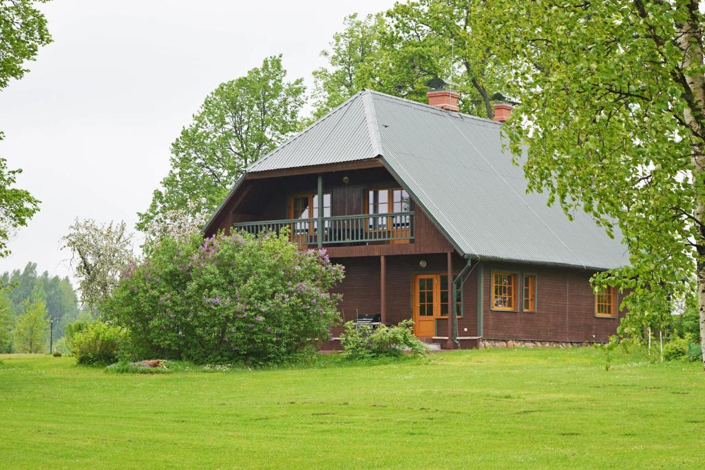 BauņiBrivdienu maja Ūtkas的绿色田野上带金属屋顶的棕色房子