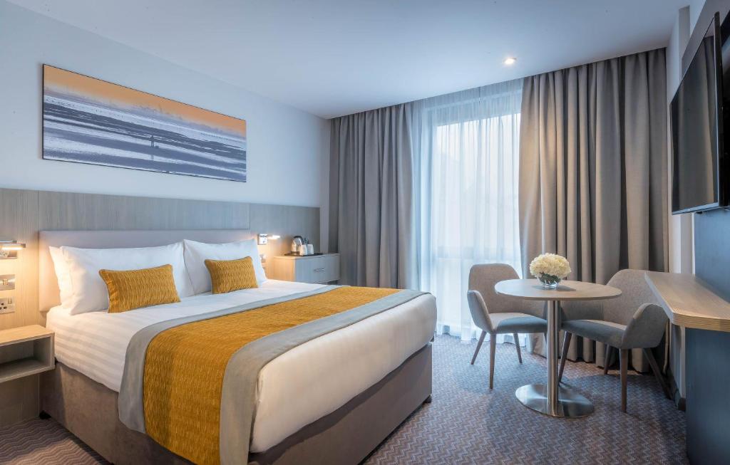 泰恩河畔纽卡斯尔Maldron Hotel Newcastle的酒店客房设有一张大床和一张桌子。
