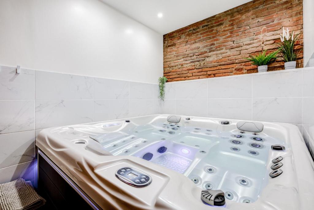 图卢兹Spa des Carmes的砖墙客房内的白色浴缸