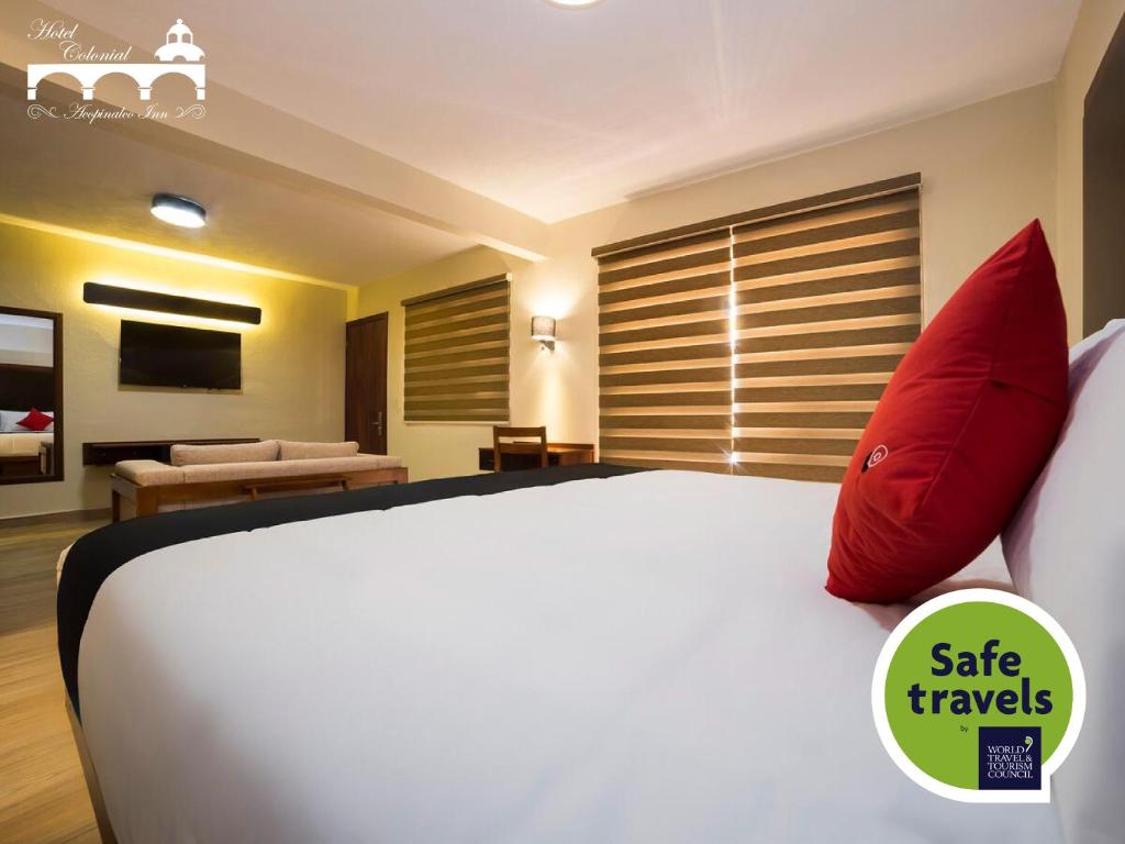 AcopinalcoHotel Colonial Acopinalco Inn的卧室配有带红色枕头的大型白色床