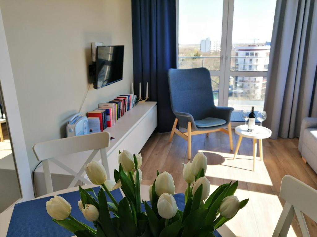 科沃布热格Cicha Przystań Apartamenty Platany的客厅配有蓝色椅子和鲜花桌