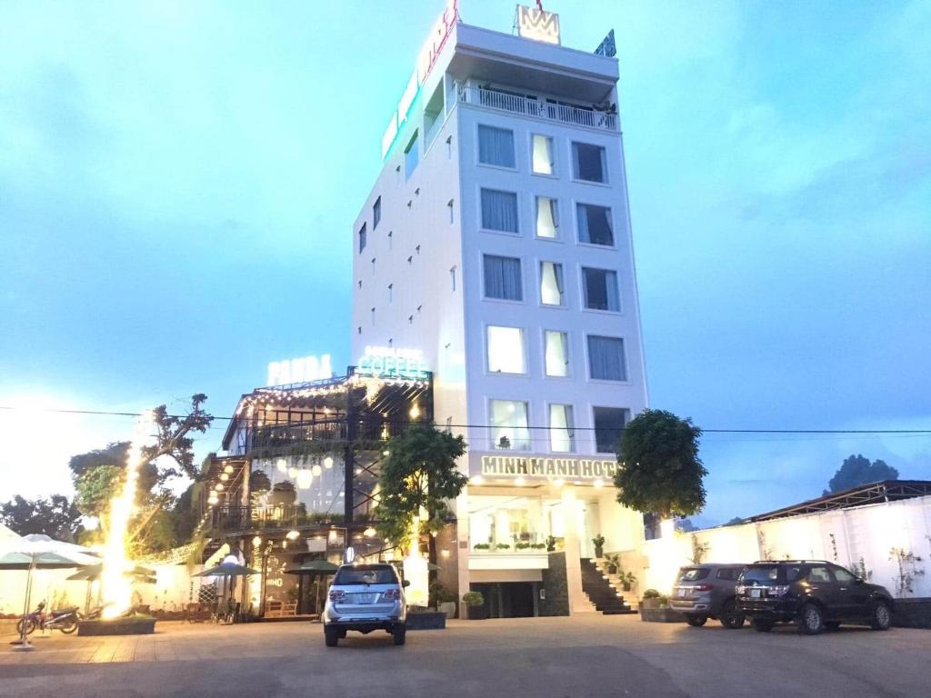 波来古市Minh Manh Hotel 2的一座高大的白色建筑,汽车停在停车场