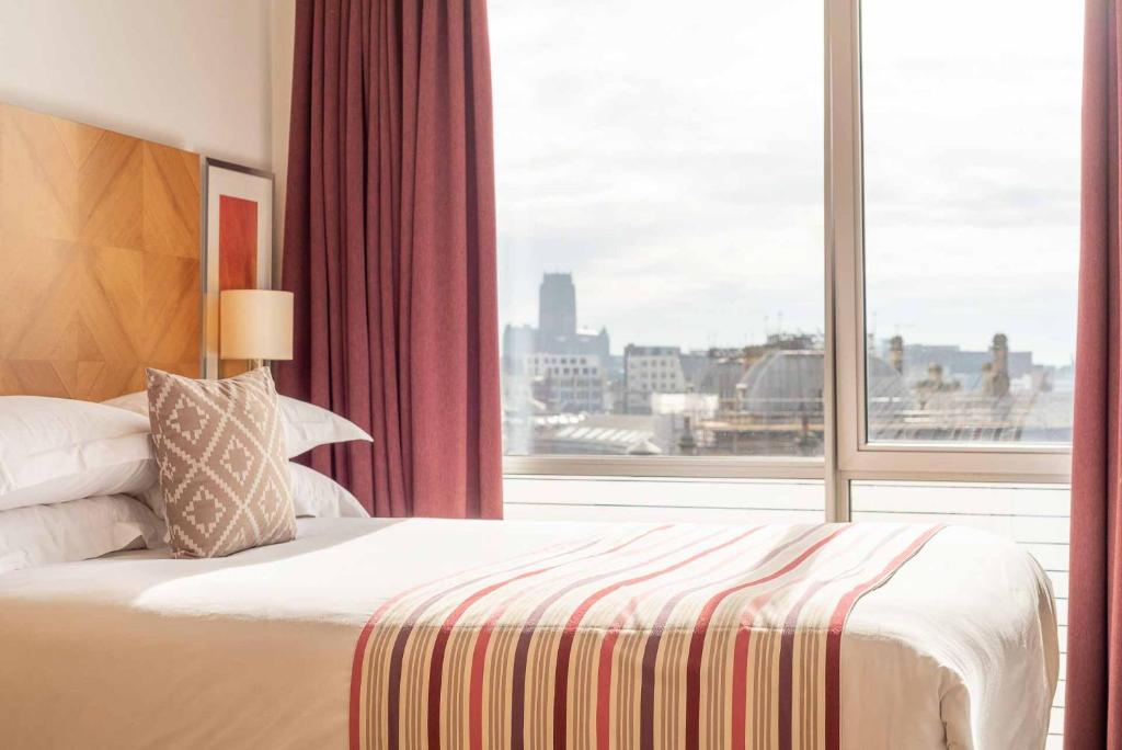 利物浦普瑞米尔利物浦套房酒店的一间卧室设有一张床和一个大窗户
