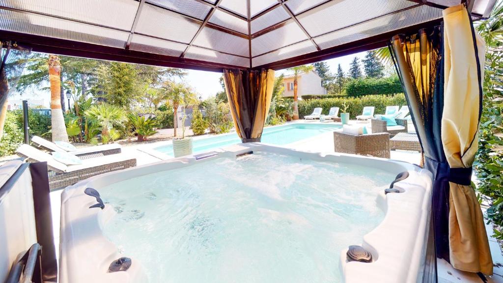 圣艾格夫Villa 35 de Saint Aygulf的享有游泳池景色的按摩浴缸