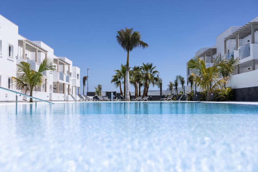 科拉雷侯Island Home Fuerteventura的一座棕榈树和建筑的大型游泳池