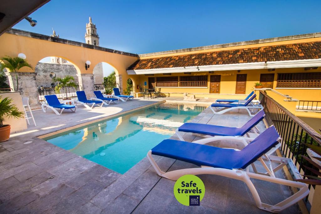 梅里达加勒比梅里达尤卡坦半岛酒店 的一座带躺椅的游泳池位于大楼旁