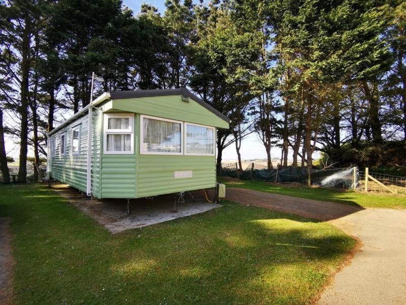 纽基Newquay Caravan Holiday的坐在草地上的绿色小房子