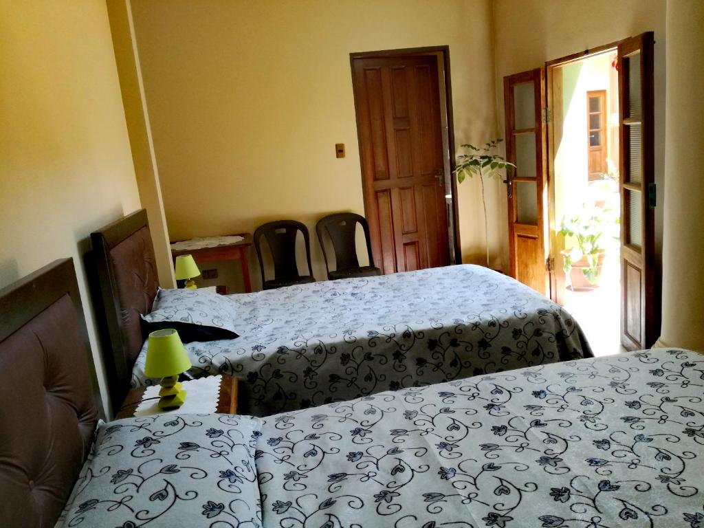 科恰班巴ALSIGAL COCHABAMBA Casa de Huéspedes的一间卧室配有两张床和一张桌椅