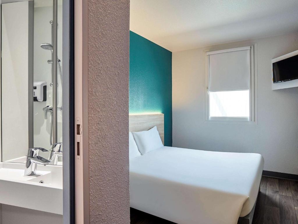 Saint-CergueshotelF1 Annemasse Hotel Renove的浴室设有白色的床和水槽。