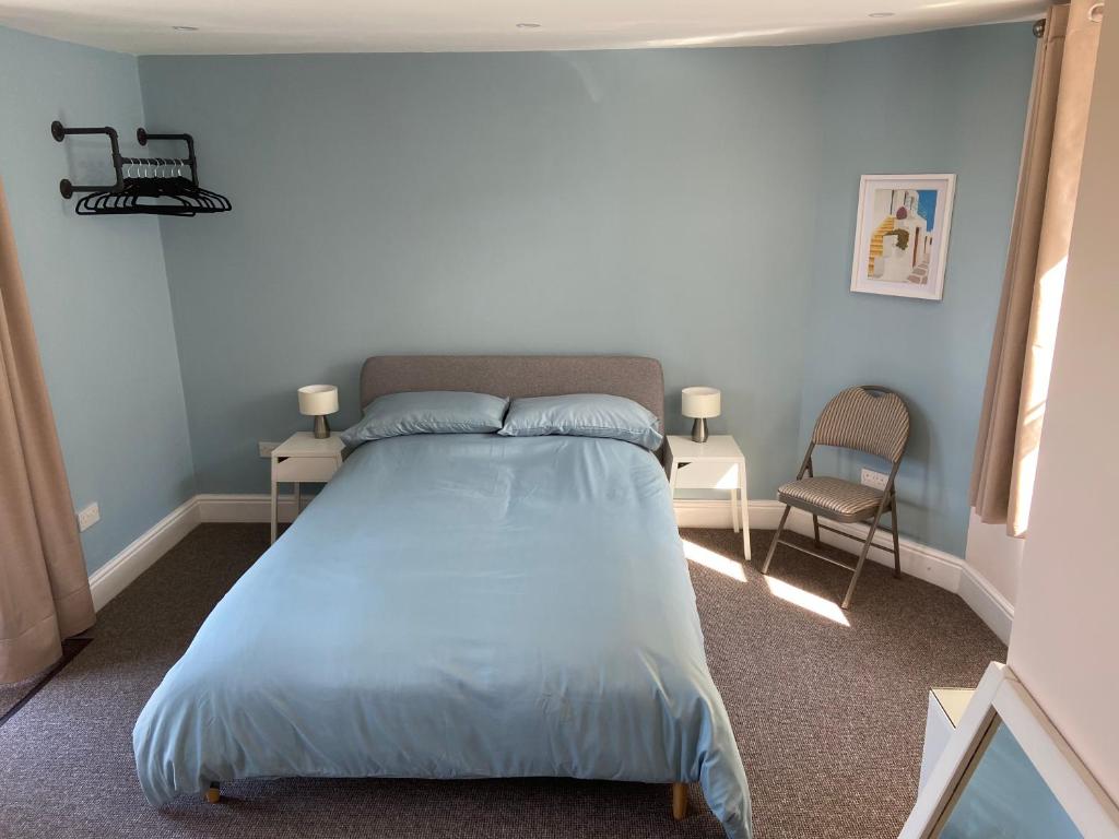 库姆马丁Homewood Airbnb, Combe Martin, Devon - 300m to the Beach!的一间卧室配有一张带蓝色床单的床和一把椅子