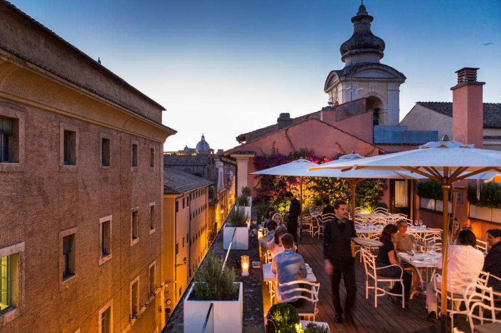 罗马DOM Hotel Roma - Preferred Hotels & Resorts的阳台,人们坐在桌子和遮阳伞下