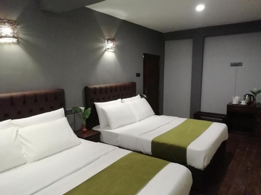 努沃勒埃利耶Tea Mount Forest的配有两张床铺的酒店客房,提供白色和绿色床单