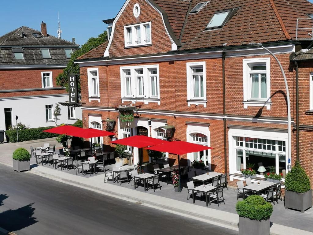 埃姆斯代滕林登霍夫酒店的大楼前的餐厅,配有桌子和红伞