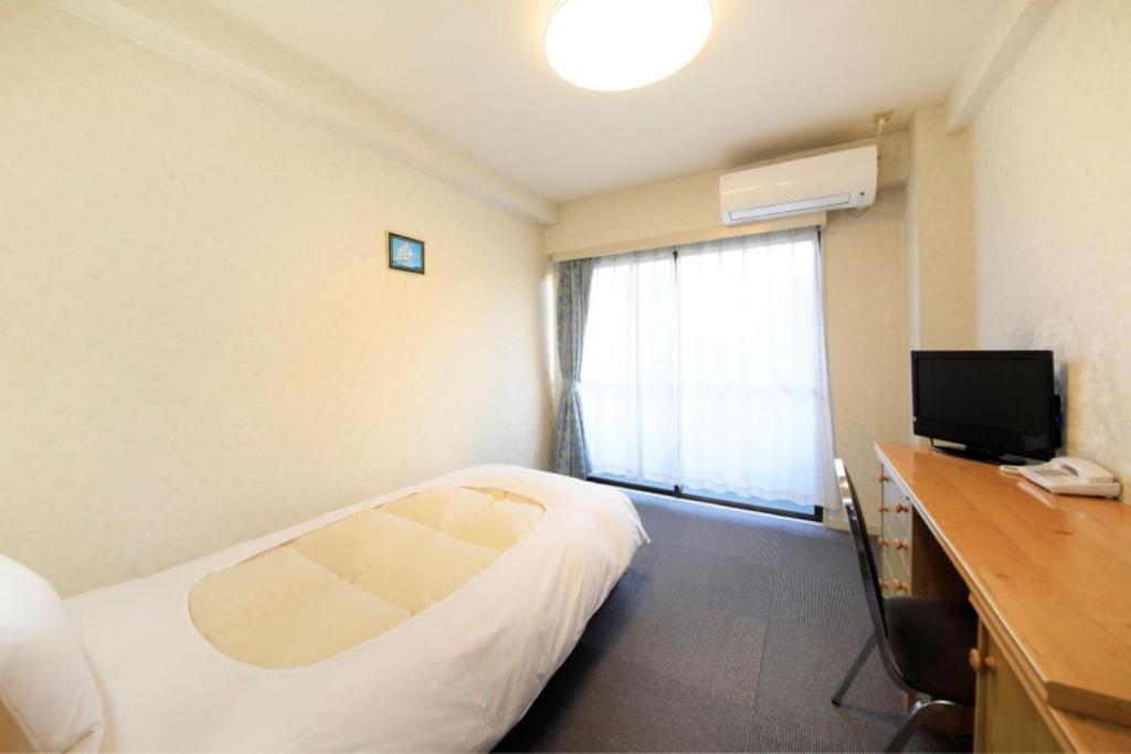 府中市Monthly Mansion Tokyo West 21 - Vacation STAY 10871的酒店客房配有一张床、一张书桌和一台电视。