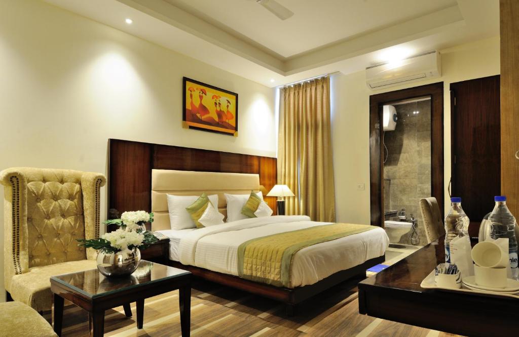 新德里Hotel Citizen New Delhi的一间卧室配有一张床、一张桌子和一张沙发