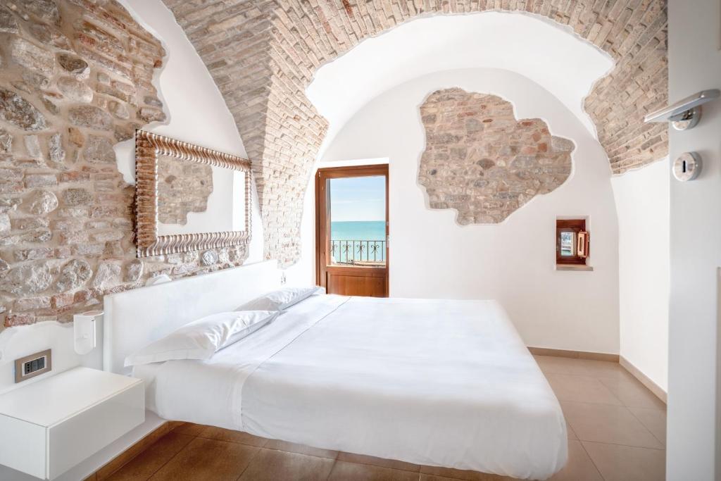 泰尔莫利洛坎达埃尔费瑞酒店的卧室配有一张白色大床,位于石墙内