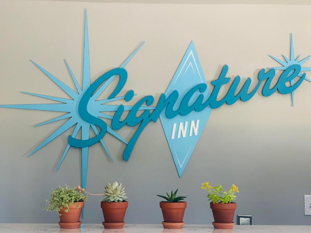 圣克拉拉Signature Inn Santa Clara的墙上的蓝色标志,有盆栽植物