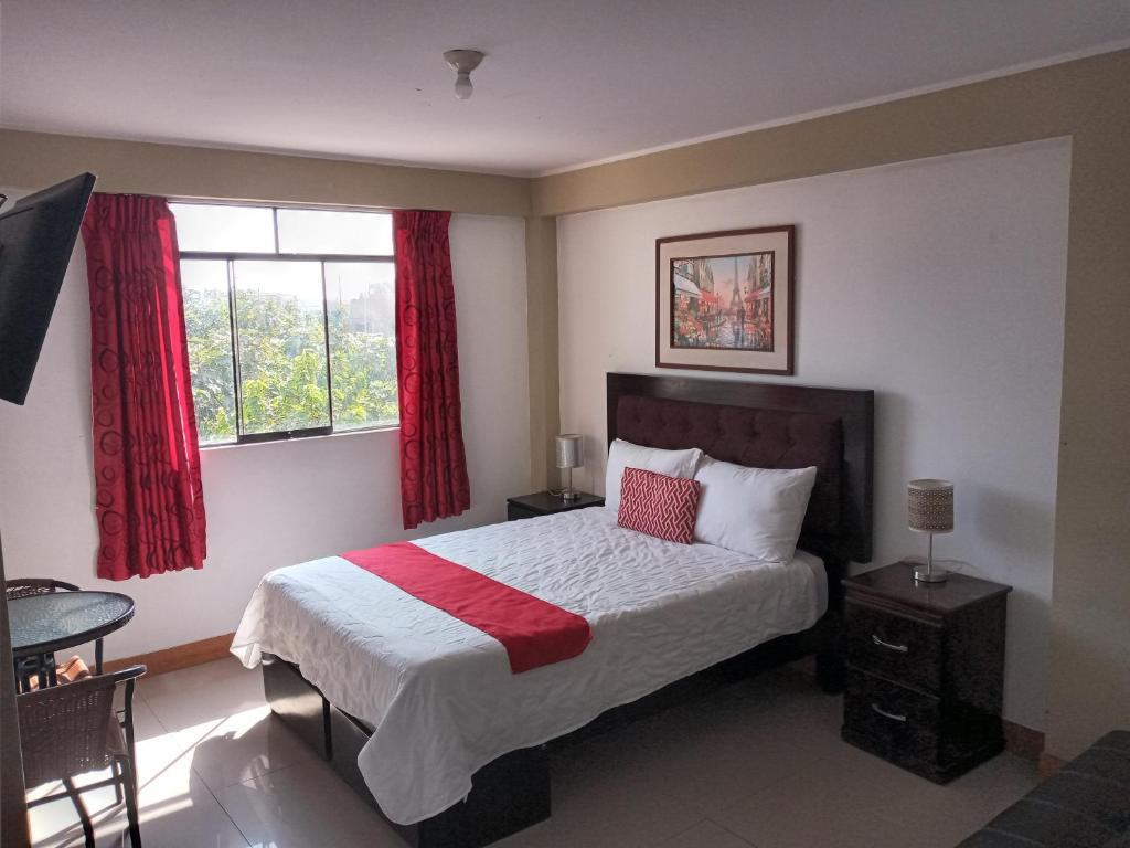 皮斯科Pisco Hotel Corina的一间卧室配有床和红色窗帘的窗户