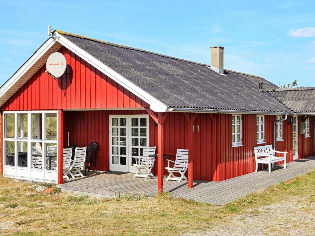 Nørre Lyngvig6 person holiday home in Hvide Sande的木制甲板上带椅子的红色谷仓