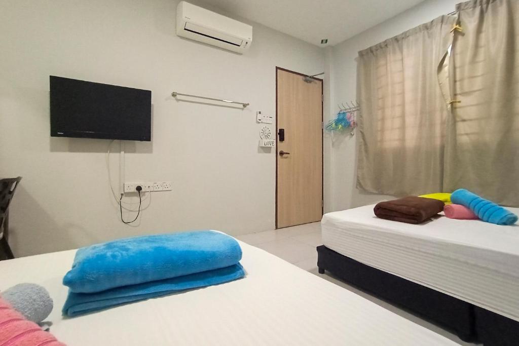 古晋Hom2rex Kuching Homestay Taman Timberland的客房设有两张床和一台墙上的电视。