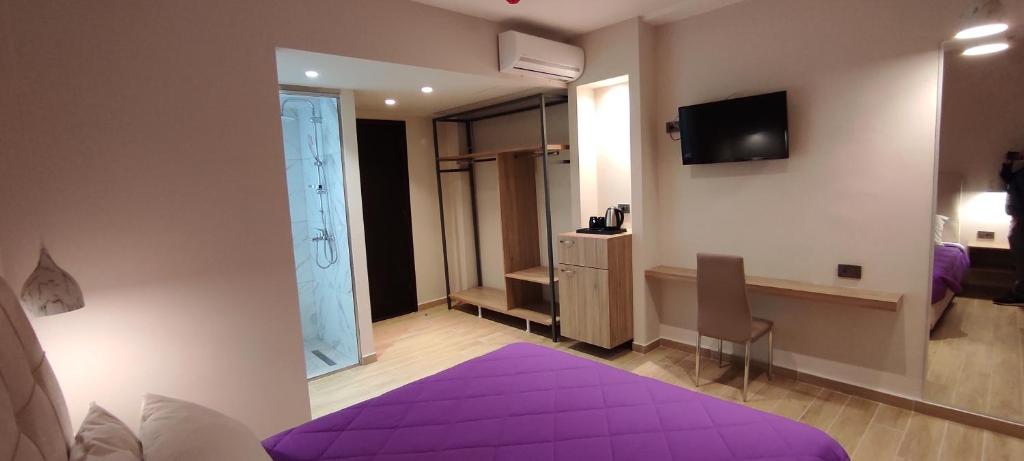 科斯镇Sonia Hotel & Suites的一间卧室配有一张紫色的床和一台电视机