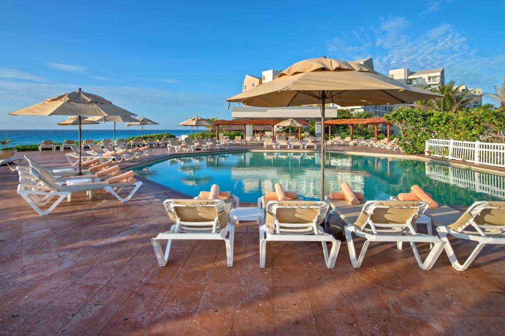 坎昆State of the Art Condos en la mejor Playa de Cancun frente a PLAZA LA ISLA的一个带躺椅和遮阳伞的游泳池