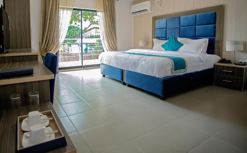 拉各斯Riviera Suites的一间卧室配有一张大床和蓝色床头板