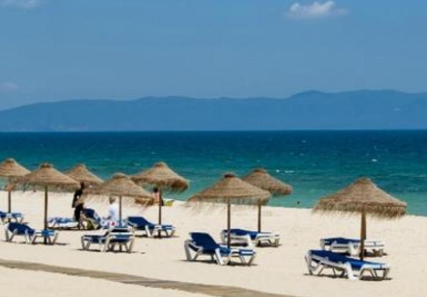 特罗亚TRÓIA BOUTIQUE APARTMENT的海滩上的一组椅子和遮阳伞