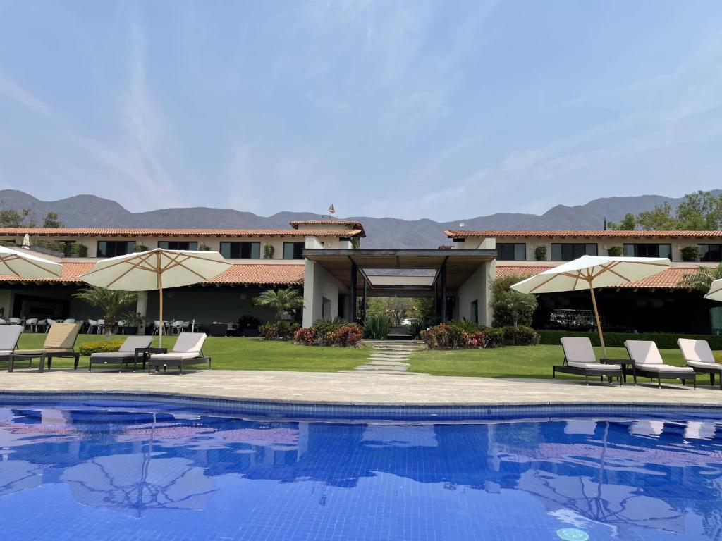 阿吉吉克La Reserva Chapala的一个带椅子和遮阳伞的游泳池的度假酒店
