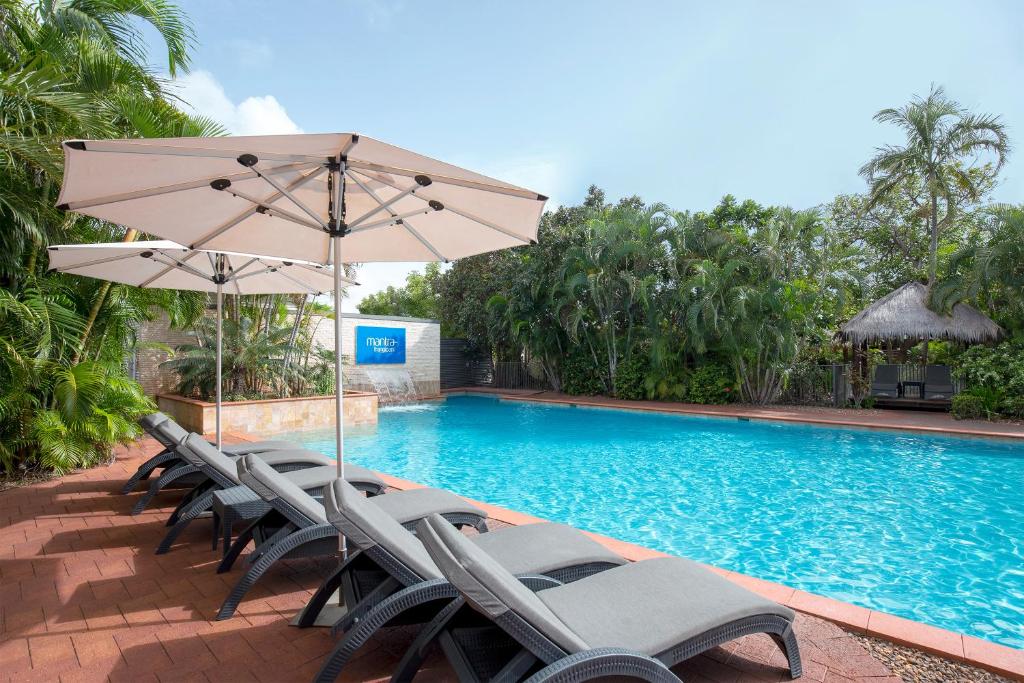 布鲁姆布鲁姆弗兰吉帕尼曼特拉公寓式酒店的一组椅子和一把遮阳伞,位于游泳池旁