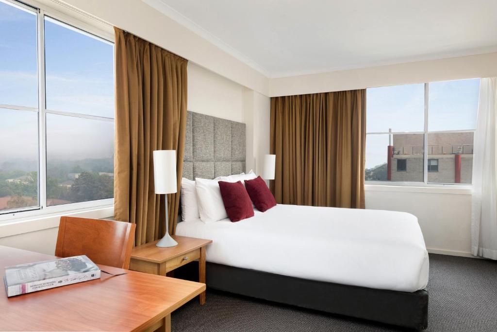 堪培拉北伯恩曼特拉酒店的酒店客房设有一张床、一张书桌和窗户。