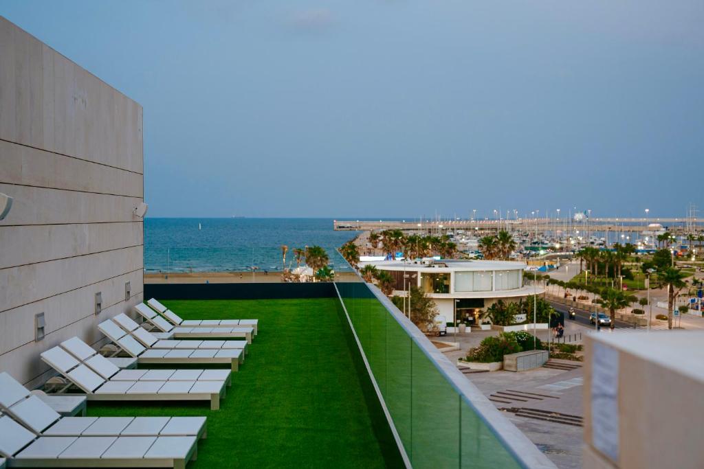瓦伦西亚Hotel Neptuno Playa & Spa的建筑物屋顶上的一排躺椅