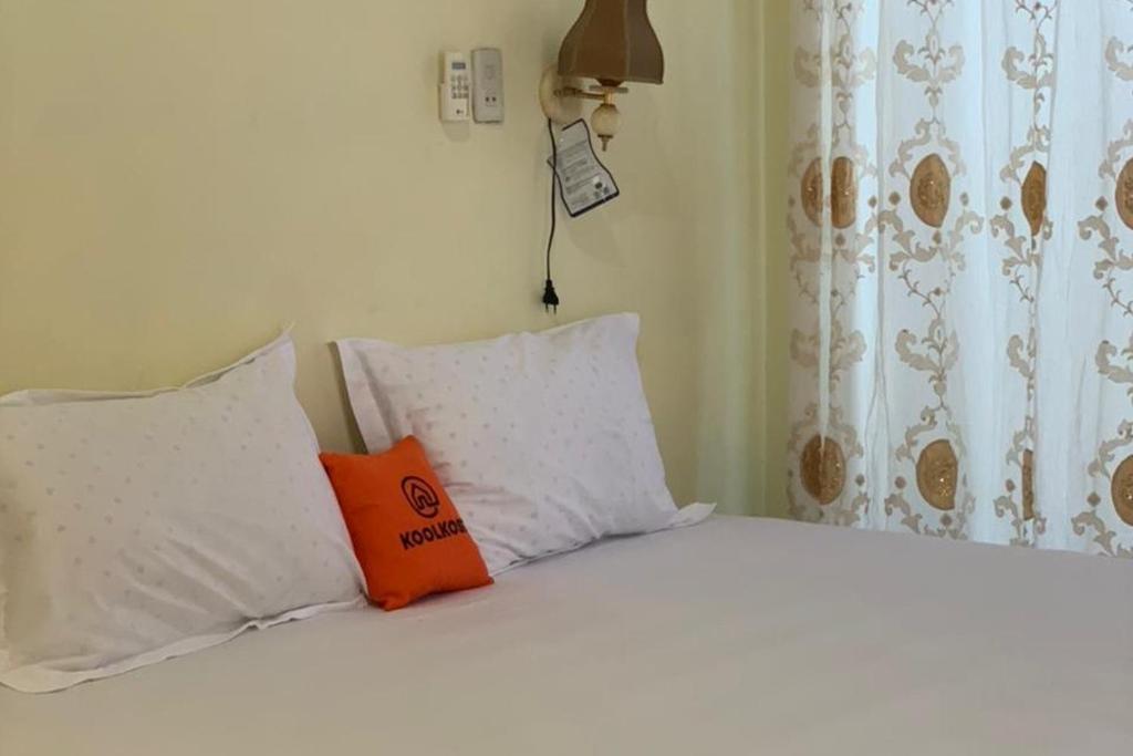 先达KoolKost near Budi Mulia Siantar的一张白色的床,上面有橙色枕头