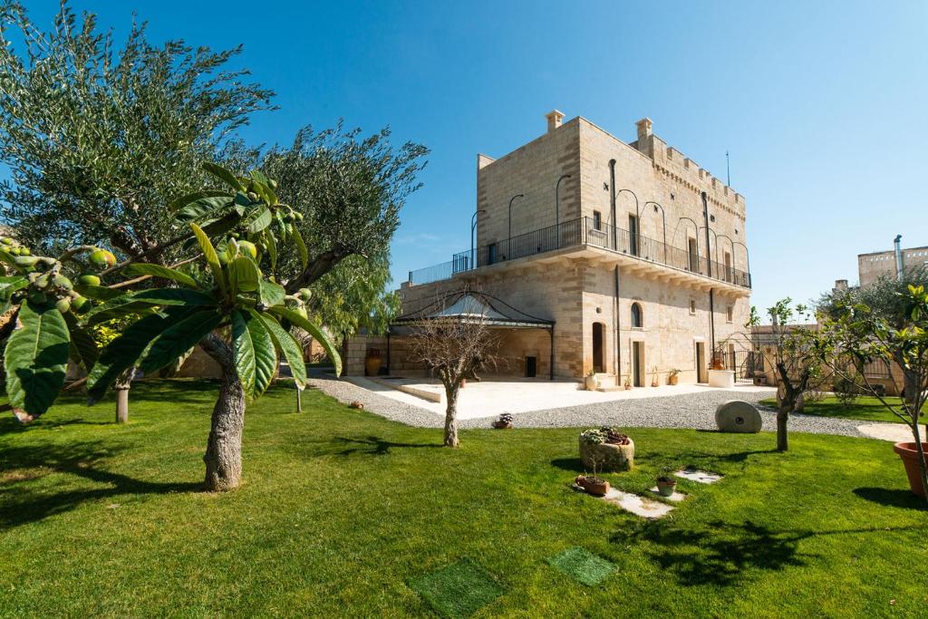 Villa CastelliMasseria Antoglia的一座古老的建筑,前面有棕榈树