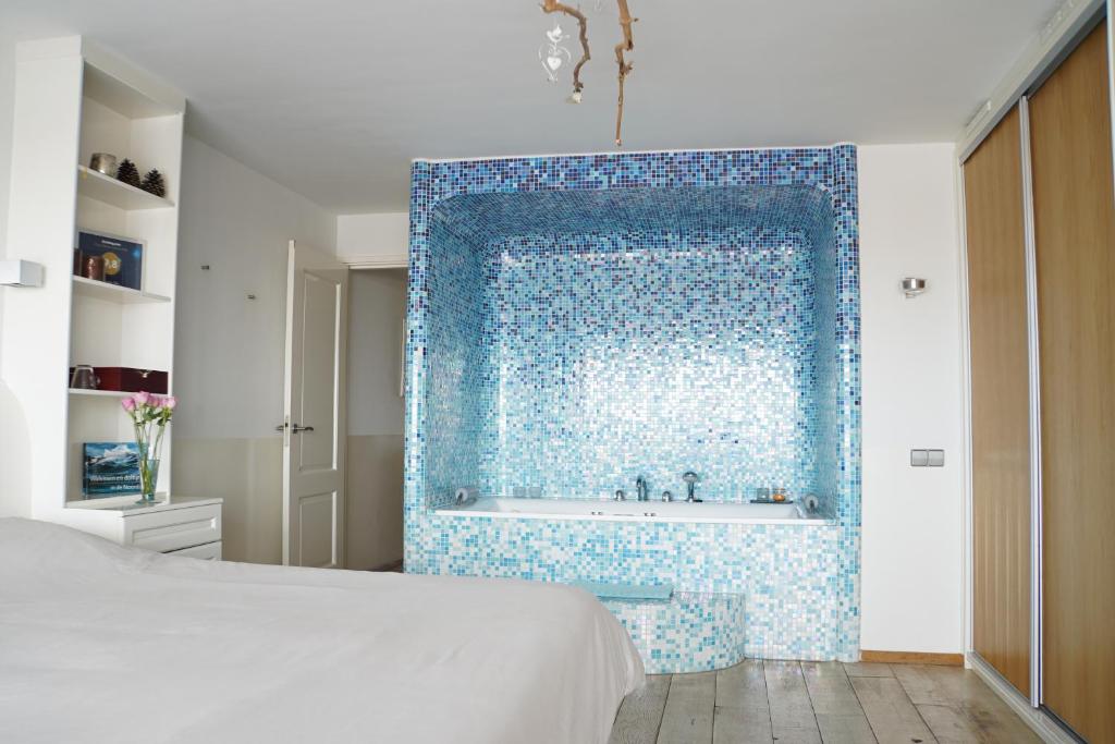 艾默伊登维他命Z住宿加早餐旅馆的卧室配有蓝色瓷砖墙和浴缸