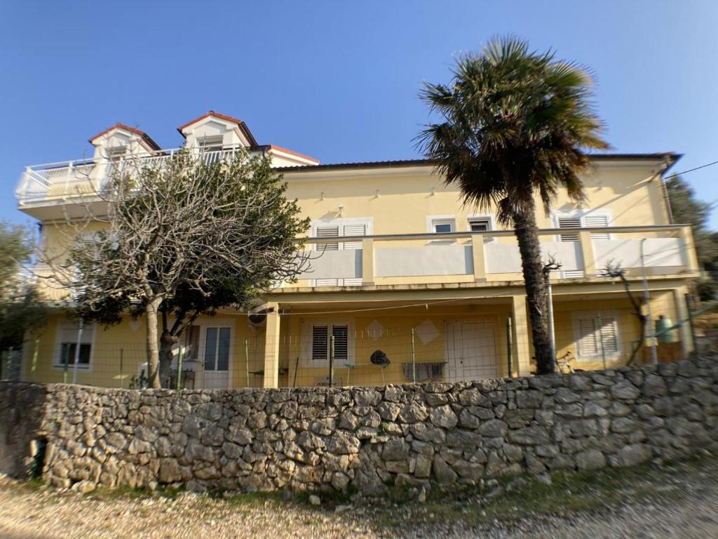 伦Apartmani Marko的一座黄色的大房子,有石墙和棕榈树