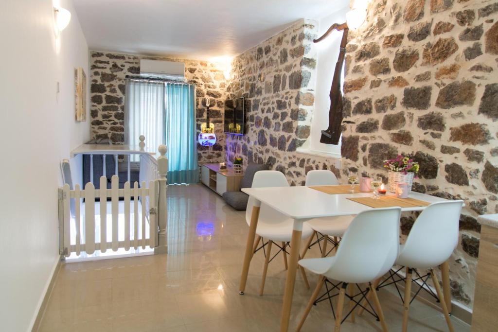 伊兹拉Sokaki House的一间设有石墙和桌椅的用餐室