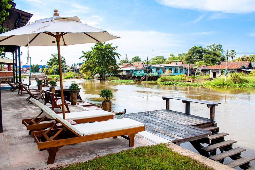 Ban Yai (1)The Bank River House Ayutthaya的一组桌椅,配有雨伞和水