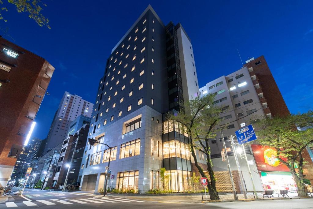 东京Almont Hotel Nippori的夜幕降临的城市街道上一座高楼