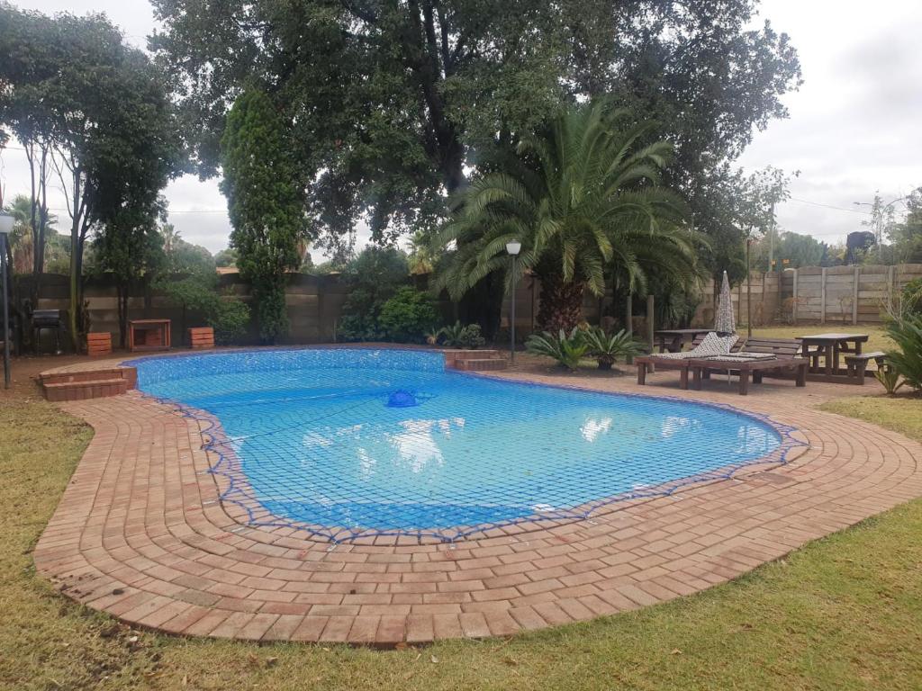 阿尔伯顿SM Africa Guest House的一座位于庭院中的游泳池,四周有砖砌的走道