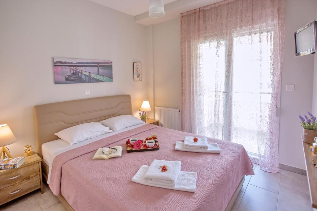 尼亚普拉莫斯Sun & Sea Luxury Apartment的一间卧室配有粉红色的床和2条毛巾