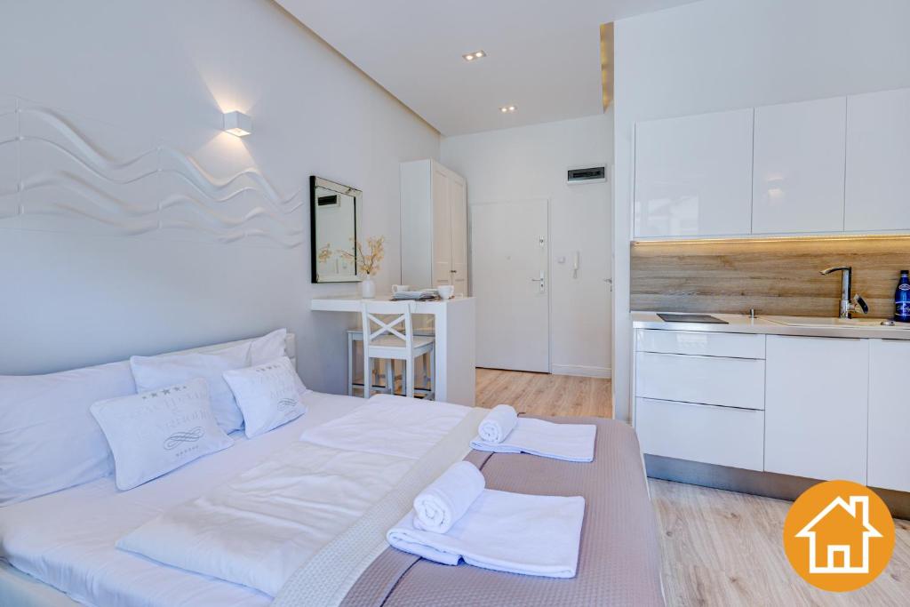 米兹多洛杰Apartamenty Marea - visitopl的一间带白色大床的卧室和一间厨房