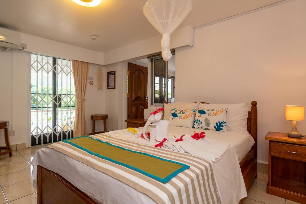 Anse a La MoucheJanes' Serenity Guesthouse的一间卧室配有一张大床,上面有红色的弓