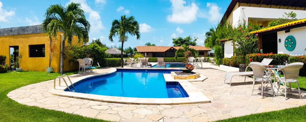 皮廷布Pousada Aconchego的一个带椅子的庭院和房子的游泳池