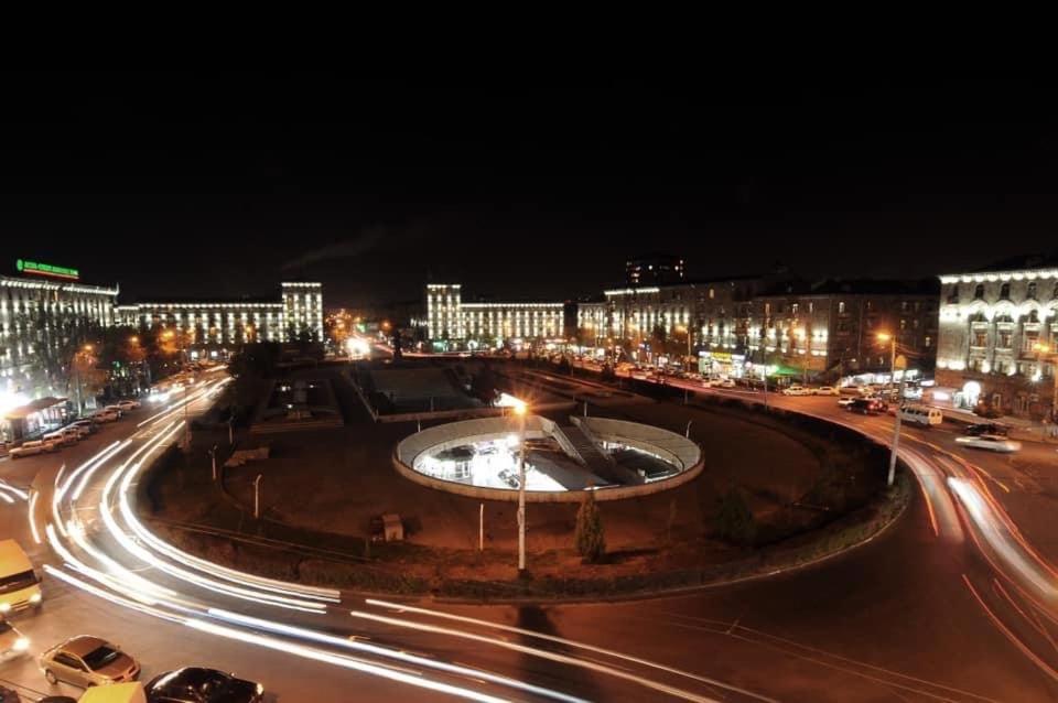 埃里温Квартира около станции метро с балконами的夜间有喷泉和建筑物的城市街道