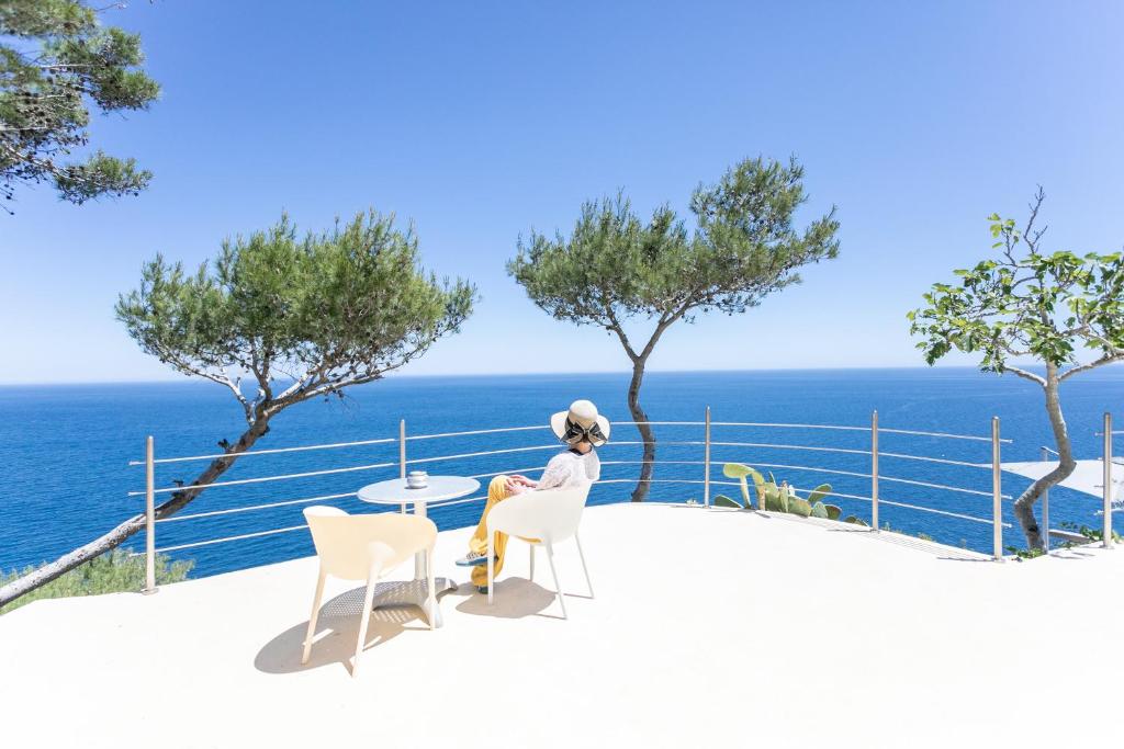 莱乌卡La Casa del Fico的坐在俯瞰大海的阳台桌子上的女人