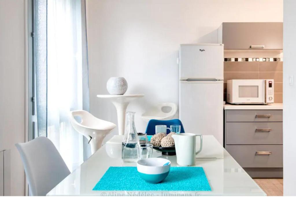 拉罗谢尔Grand studio chaleureux à Port Neuf的厨房配有白色桌子和白色冰箱。