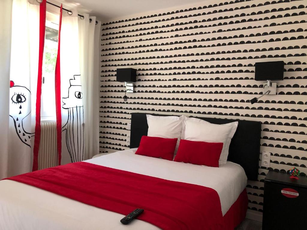 马孔协和酒店的一间卧室配有一张带红色枕头的大床