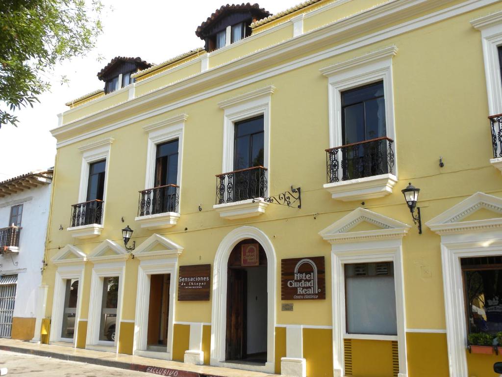 圣克里斯托瓦尔-德拉斯卡萨斯雷阿尔城历史中心酒店的黄色的建筑,设有窗户和阳台